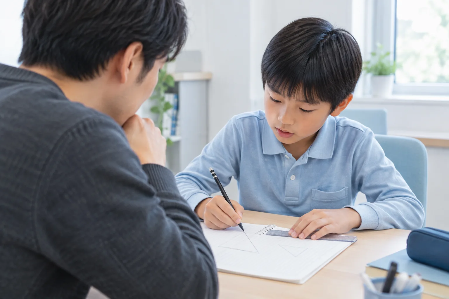 図形について考えながらノートに書き込む小学生と、見守る講師の学習イメージ